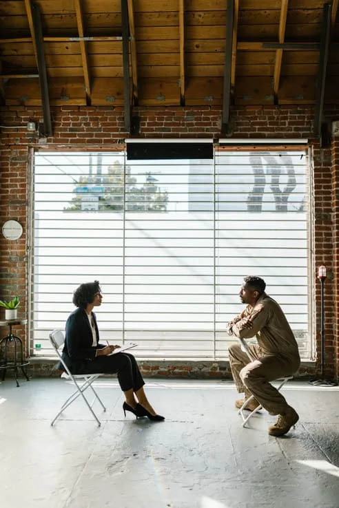 photo of a therapist and client sitting in metal chairs across from each other